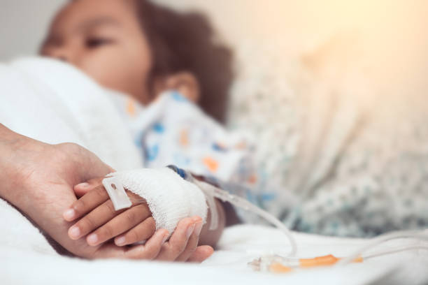 Mother hand holding child hand who have IV solution in the hospital with love and care stock photo