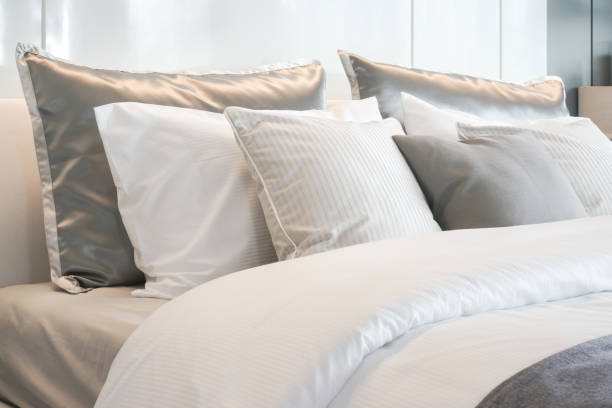 istock Gray color scheme pillows setting on bed with satin finished style bedding 817198162