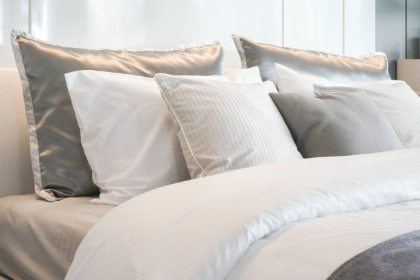 Gray color scheme pillows setting on bed with satin finished style bedding stock photo