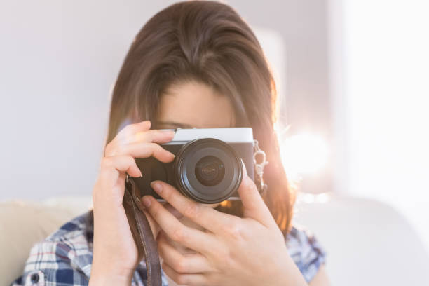 istock Pretty brunette taking a picture with retro camera on couch 817213870
