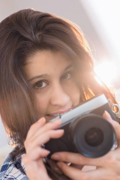 istock Pretty brunette taking a picture with retro camera on couch 817216248