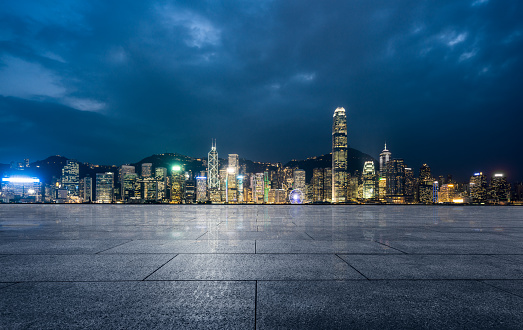 empty brick platform with Hong Kong skyline in background at night.