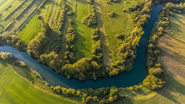 River bend surrounded by fields from bird's eye view. stock photo