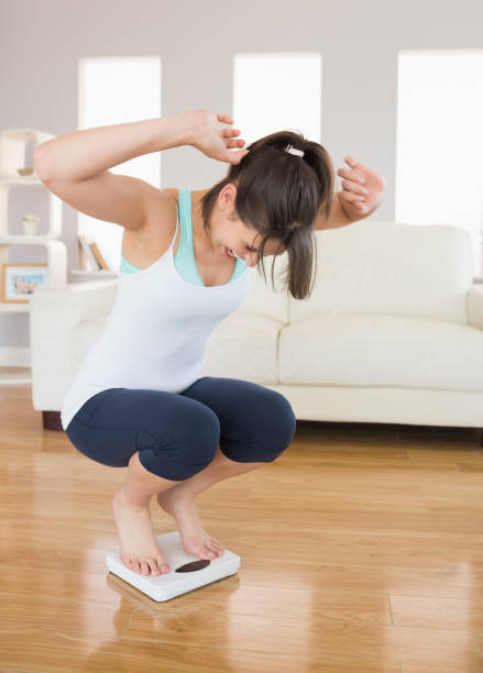 istock Fit brunette cheering on the weighing scales 817233936