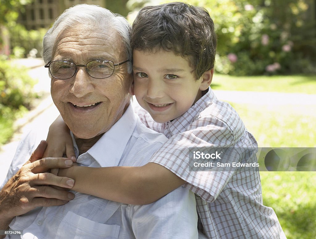 Senior hombre sentado al aire libre con young boy ser Cariñoso a - Foto de stock de 4-5 años libre de derechos