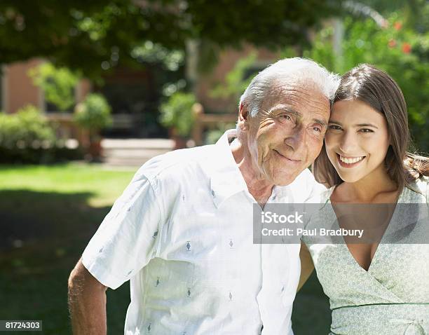 Senior Man Standing Outdoors With Arm Around Woman Smiling Stock Photo - Download Image Now