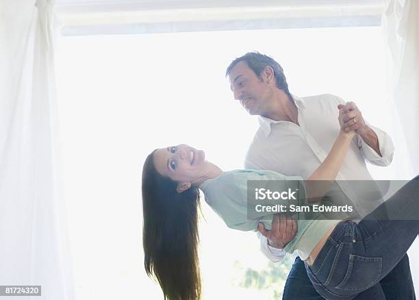 Pareja Bailando Cerca De La Ventana Amplia Y Sonriendo Foto de stock y más banco de imágenes de Bailar