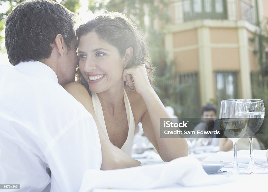 Couple at outdoor party whispering and smiling  Bonding Stock Photo