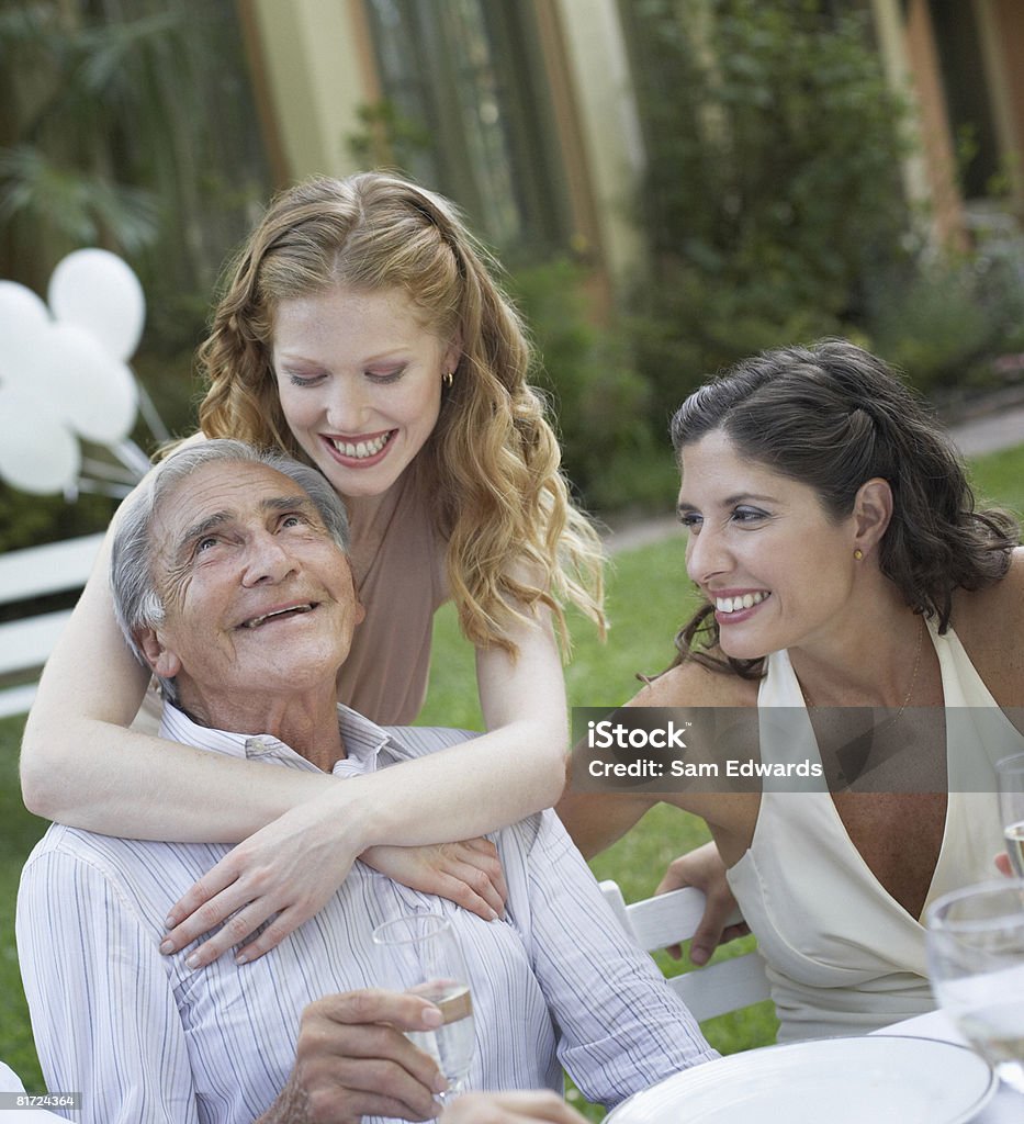Trois personnes dans une fête en plein air souriant et être Affectueux - Photo de Famille multi-générations libre de droits