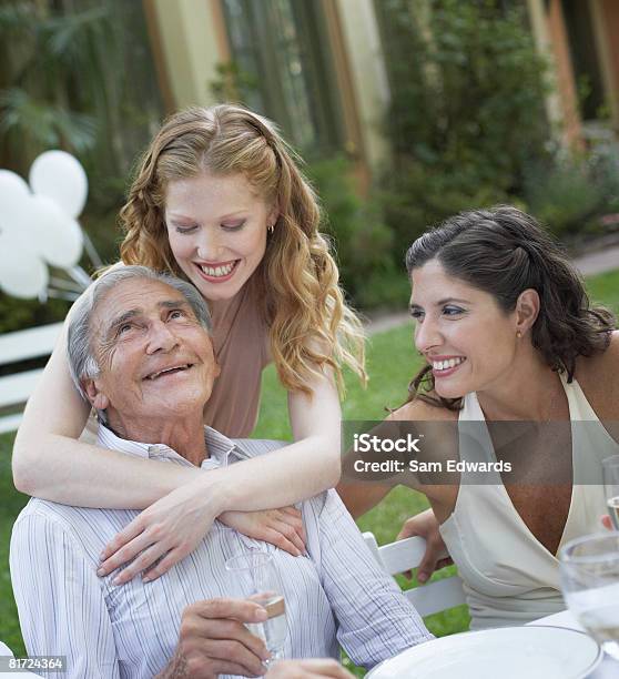 Photo libre de droit de Trois Personnes Dans Une Fête En Plein Air Souriant Et Être Affectueux banque d'images et plus d'images libres de droit de Famille multi-générations