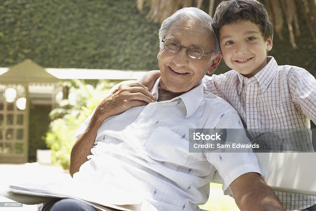 Outdoor uomo anziano seduto sulla panchina con giovane ragazzo - Foto stock royalty-free di Etnia latino-americana