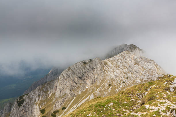 istock Limestone cliffs covered in fog and clouds in the Alps 817263756