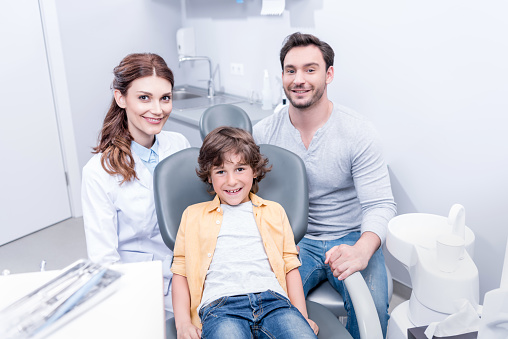 little smiling boy with father and dentist at dentist office