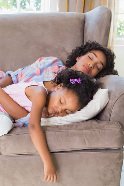istock Pretty mother sleeping with her daughter on the couch 817293688