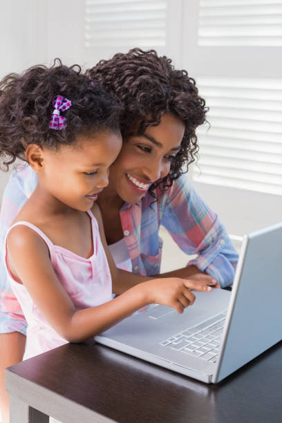 istock Cute daughter using laptop at desk with mother 817298330