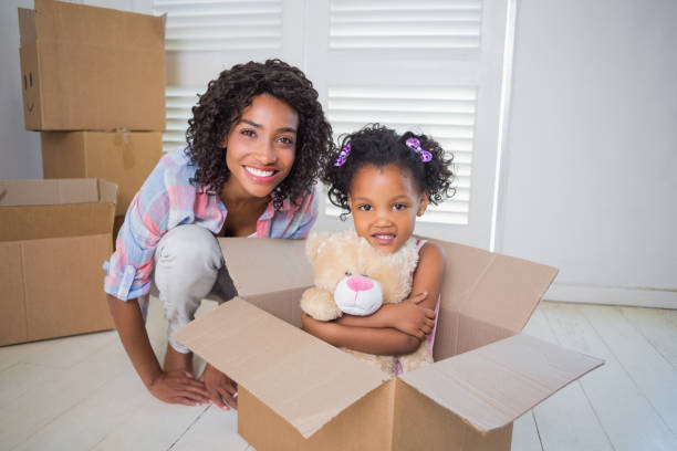 istock Cute daughter sitting in moving box with mother 817298732