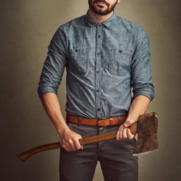 Photo of halloween male furious character hold sharp ax isolated on dark misty mysterious background.