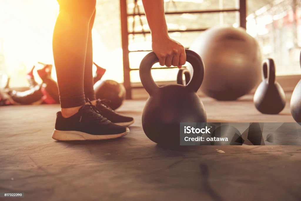 Fitness training with kettlebell in sport gym. Fitness training with kettlebell in sport gym with sunlight effect. Exercising Stock Photo
