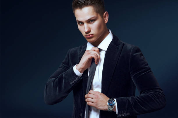 istock elegant man in black suit and tie on blue background 817325080
