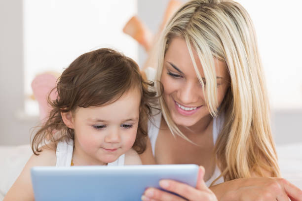 istock Mother and daughter using digital tablet on bed 817328626