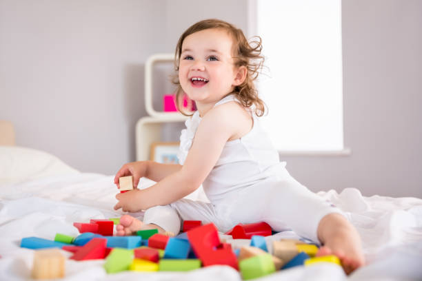istock Cute girl playing with building blocks on bed 817331562