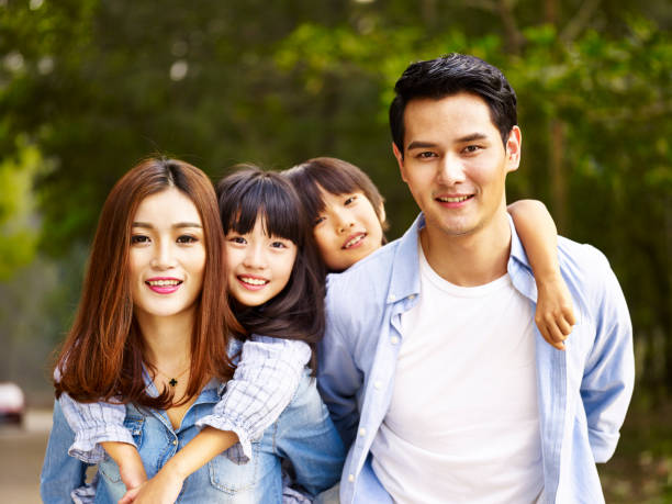 asian family taking a walk in park happy asian family with two children taking a walk in wooded park. happy malay couple stock pictures, royalty-free photos & images