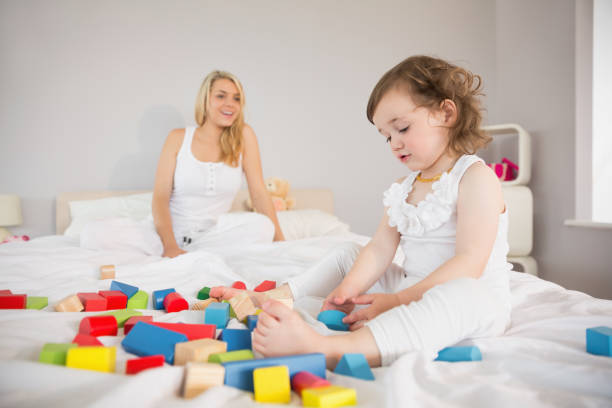 istock Mother and daughter playing with building blocks on bed 817334308