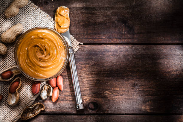 jar of peanut butter and peanuts in a shell on a white table, side view, fresh ground crushed nuts, side view