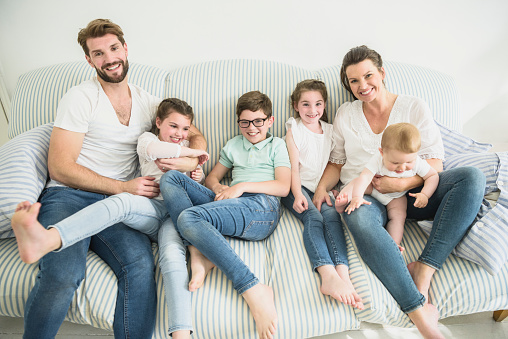 Two parents with their two daughters and two sons at home spending time together relaxing