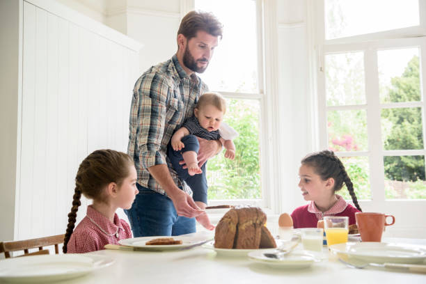 istock Father holding baby son serving breakfast to two daughters 817348062