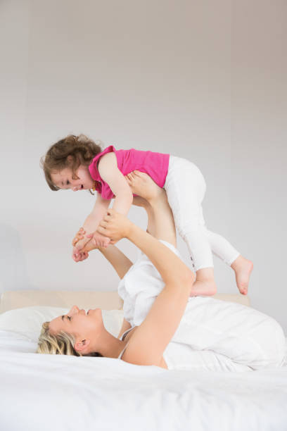 istock Young woman playing with daughter in bed 817348428