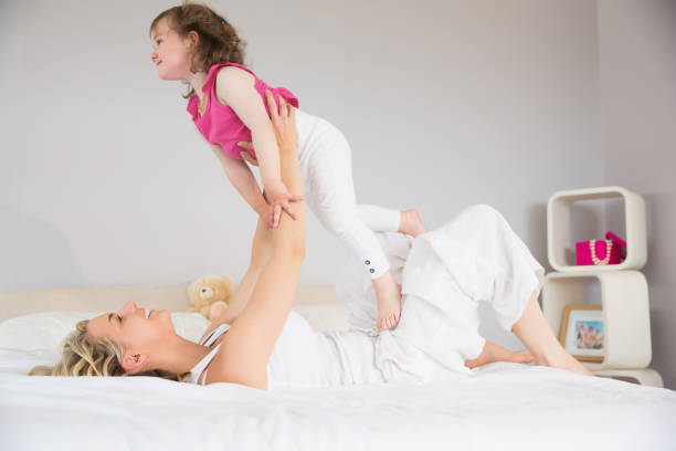 istock Young woman playing with daughter in bed 817348636