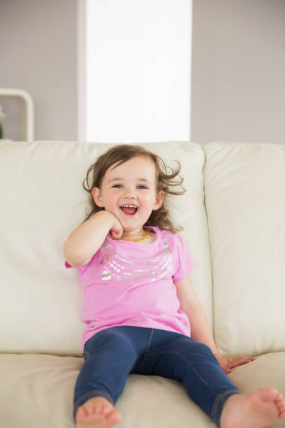 istock Cute little girl sitting on sofa at home 817348712