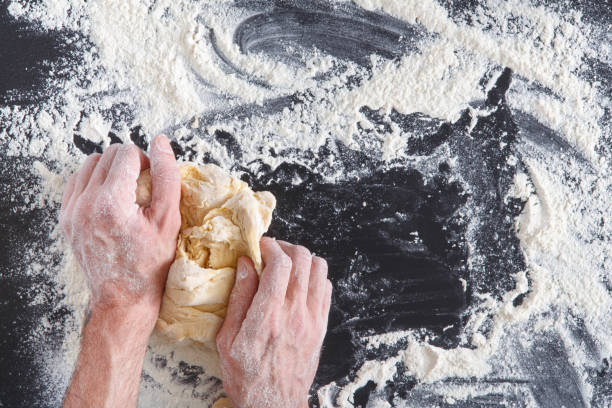 istock Hands top view knead dough on black background 817355920