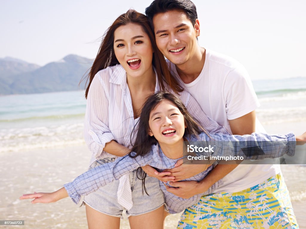 asian family having fun on beach young asian couple carrying daughter having fun on beach. Family Stock Photo