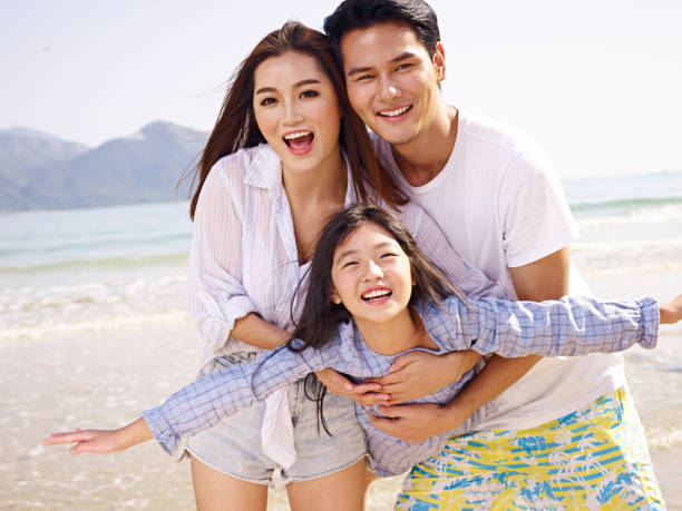 asian family having fun on beach young asian couple carrying daughter having fun on beach. happy malay couple stock pictures, royalty-free photos & images