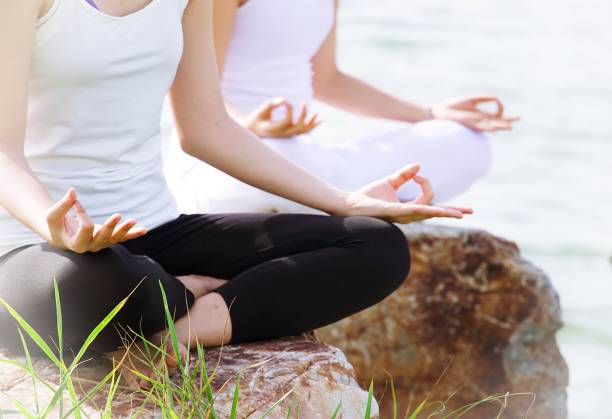 istock Two woman are meditating at seaside on the rock 817367574
