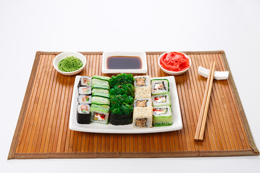 Japanese food restaurant delivery - sushi maki, unagi and roll platter set on mat isolated on white background