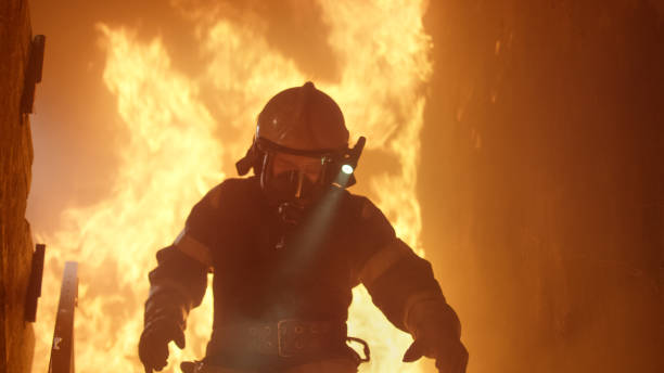 istock Brave Firefighter With Switched On Flashlight on His Helmet Runs Down the Burning Stairs. Fire is Raging. 817388390
