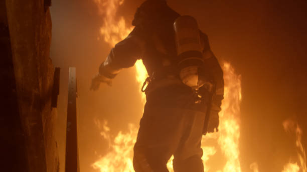 istock Brave Firefighter Runs Up The Stairs. Raging Fire is Seen Everywhere. 817388412