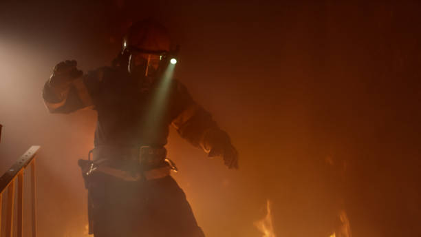 istock Brave Firefighter With Switched On Flashlight on His Helmet Runs Down the Burning Stairs. Fire is Raging. 817388426