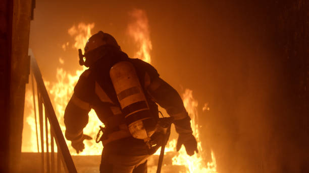 istock Brave Firefighter Runs Up The Stairs. Raging Fire is Seen Everywhere. 817388436