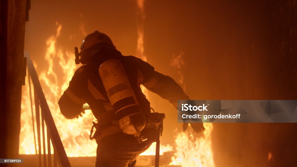 Pompier courageux s’exécute dans l’escalier. Violent incendie est vu partout. - Photo de Feu libre de droits