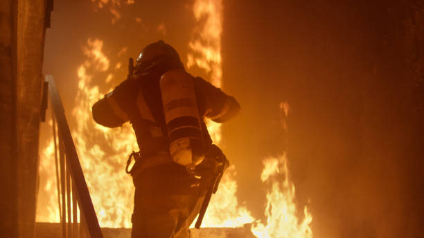 istock Brave Firefighter With Oxygen Cylinder Runs Up The Stairs. Raging Fire is Seen Everywhere. 817389126