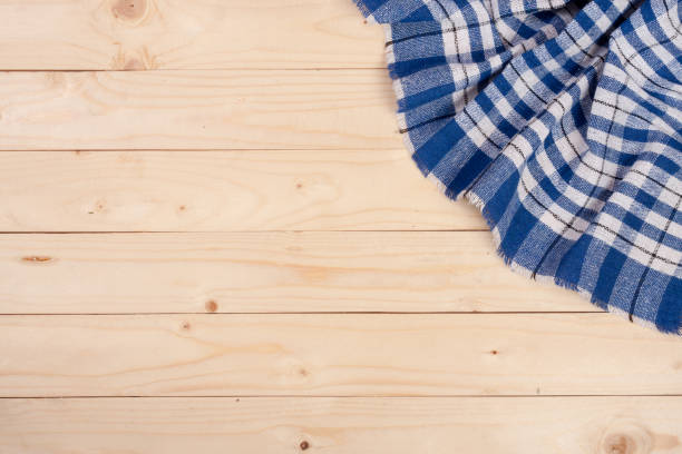 istock blue checkered tablecloth on a light wooden table with copy space for your text. Top view 817395462