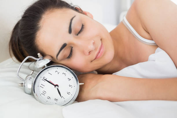 istock Beautiful woman sleeping in bed with alarm clock 817400860