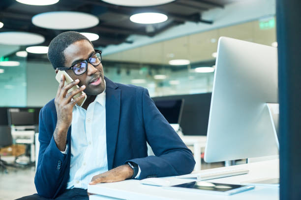 istock Smiling African Businessman Speaking by Phone in Office 817401274