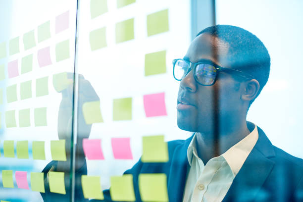 istock Modern African Businessman Putting Stickie Notes on Glass Wall 817401382