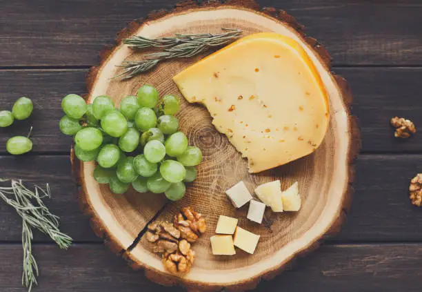 Photo of Cheese platter, gouda herb on natural wood disc with grapes and