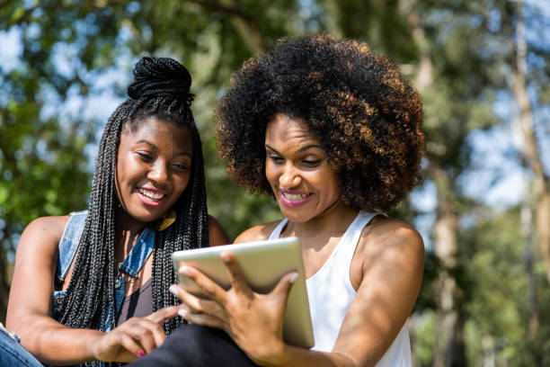 istock Afro friends using digital tablet in the park 817409562